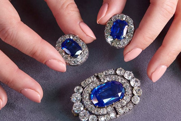 Mains aux ongles manucurés mettant en valeur des bijoux en saphir et diamant rangés en toute sécurité à la maison dans une boîte
