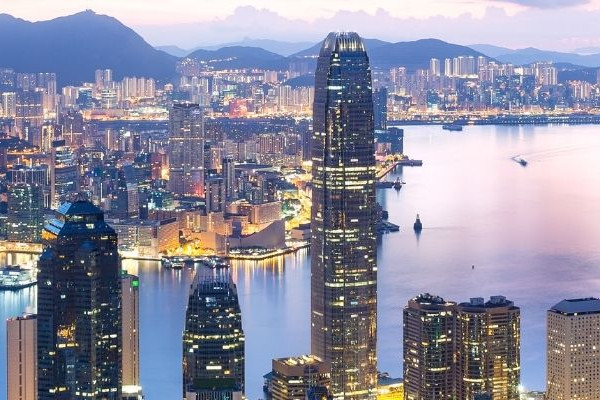 香港維多利亞港夜景全景，兩岸高樓與海面燈光倒影交織，遠山輪廓清晰，展現繁華城市天際線