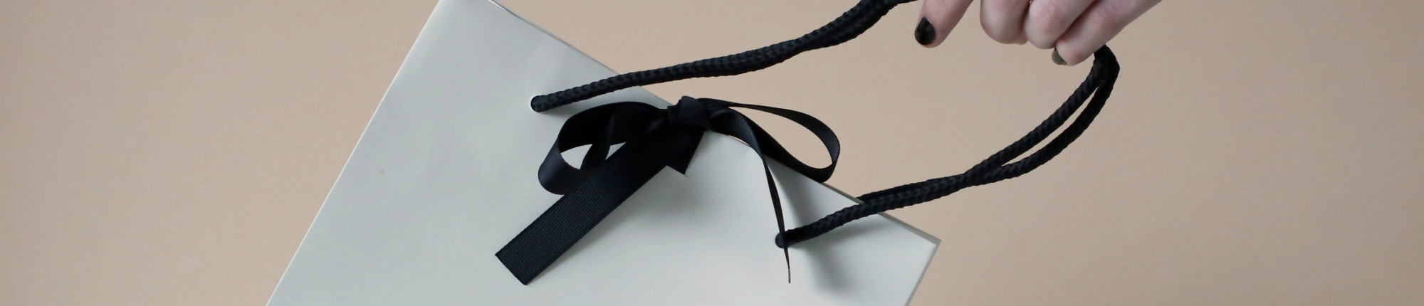 Woman holds BAUNAT gift bag with black ribbon - BAUNAT