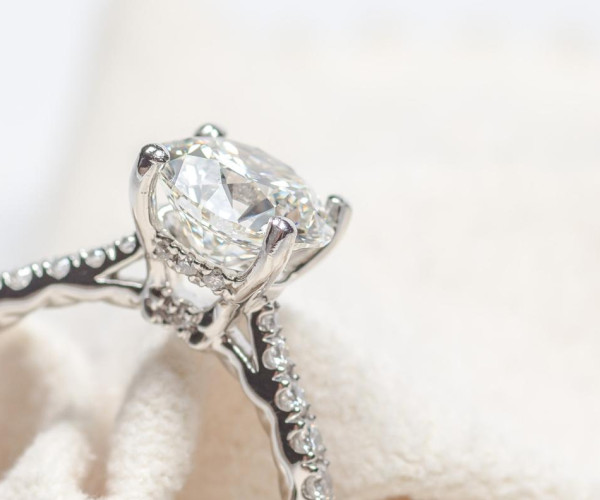 A cathedral engagement ring featuring a diamond, elegantly displayed on a pristine white cloth