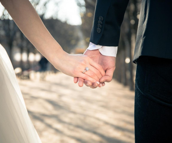 A couple holding hands in a park, showcasing their love and the charm of wedding ring superstitions around them