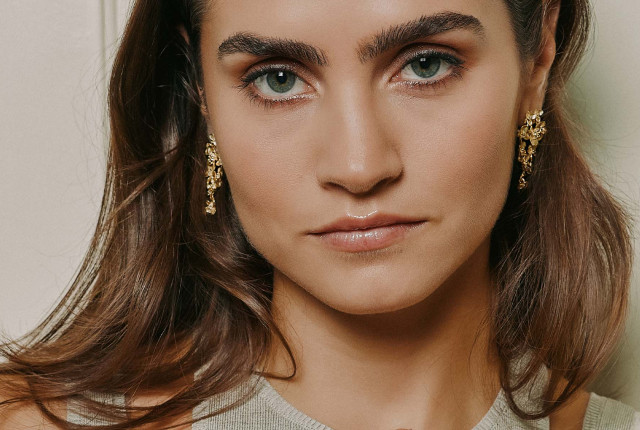 Donna con orecchini lunghi in oro giallo, design floreale a cascata, senza pietre visibili