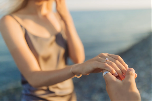 Donna che riceve una proposta di matrimonio sulla spiaggia con uno splendido anello di fidanzamento con diamante