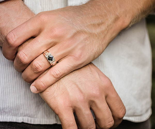 uomo che indossa un anello di fidanzamento con diamanti incastonati, simbolo dell'imminente unione con sua moglie 