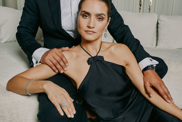 Donna con abito nero e gioielli in diamanti: orecchini pendenti, bracciale e anello a fiore in oro bianco