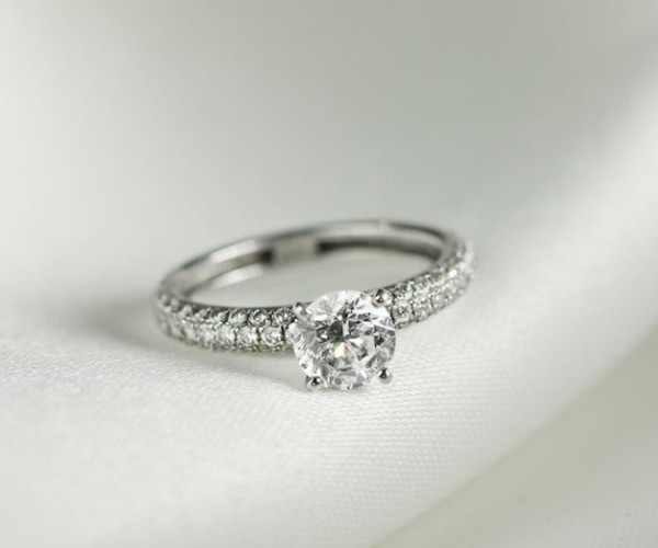 プラチナのソリティア婚約指輪、中央にラウンドカットのダイヤモンド、アーム全体にメレダイヤを敷き詰めた上品なデザイン
