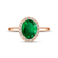 Halo ring in red gold with an oval emerald