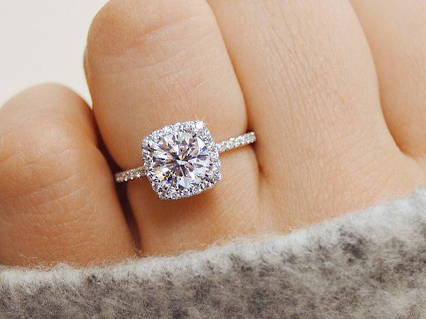 プラチナの細身リングに、ラウンドダイヤモンドをスクエアのメレダイヤ枠で囲んだソリティア婚約指輪を指に着用した接写