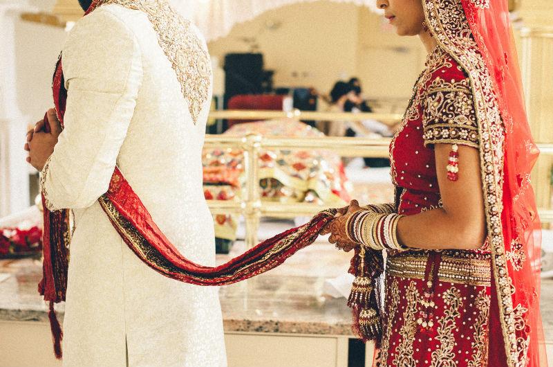 La novia india lleva un sari rojo y pulseras, joyas y anillos de oro - BAUNAT