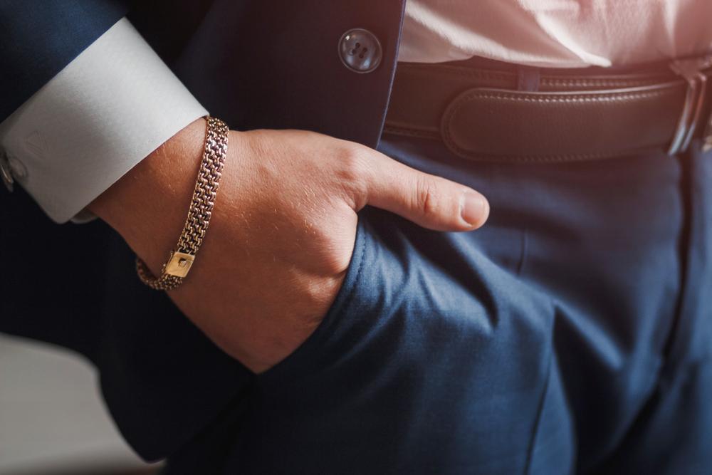 Close-up van gouden armband om pols van zakenman. Het perfecte cadeau voor hem volgens BAUNAT. 