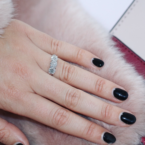 Vrouw met zwarte nagellak draagt een moderne trilogiering van BAUNAT met drie diamanten.