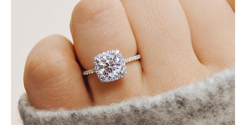 Wittegouden verlovingsring met ronde diamant in halozetting op een vinger