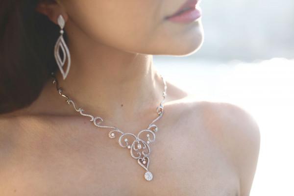 bruid met prachtige witgouden diamanten oorbellen en een ketting 