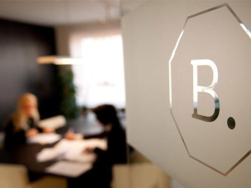 BAUNAT glass logo with a minimalist gold B inside an octagonal outline