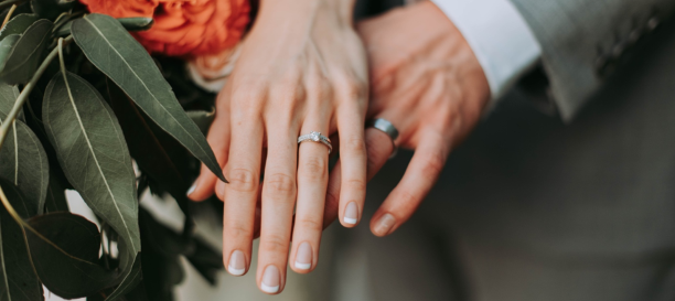 Manos entrelazadas con anillo de oro blanco con diamantes talla brillante en estilo pavé