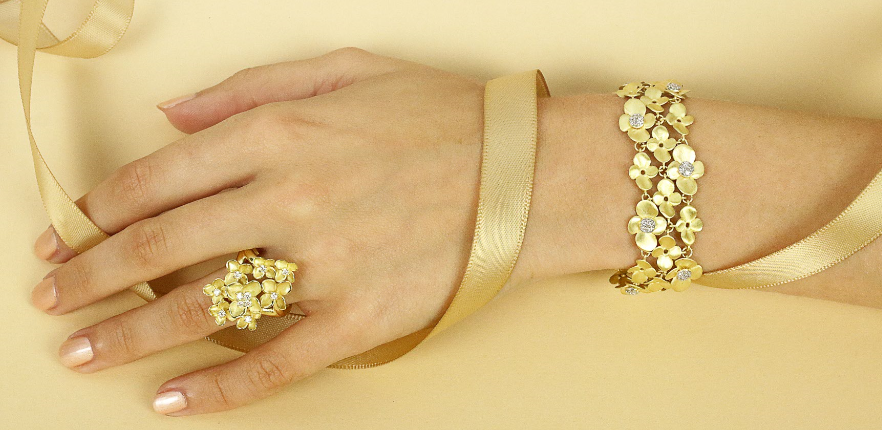 Femme portant une bague et un bracelet avec des pendentifs de fleurs et des diamants - BAUNAT
