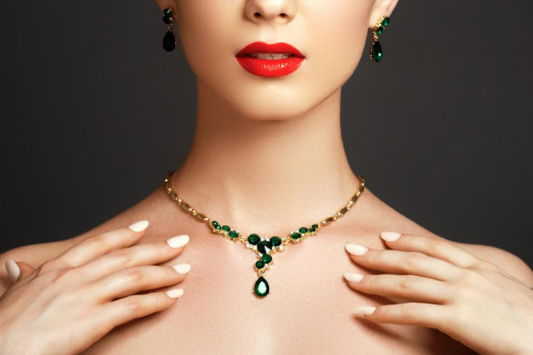 La mujer lleva un collar de oro para las damas con esmeralda. Encuentra collares de colores en BAUNAT. 