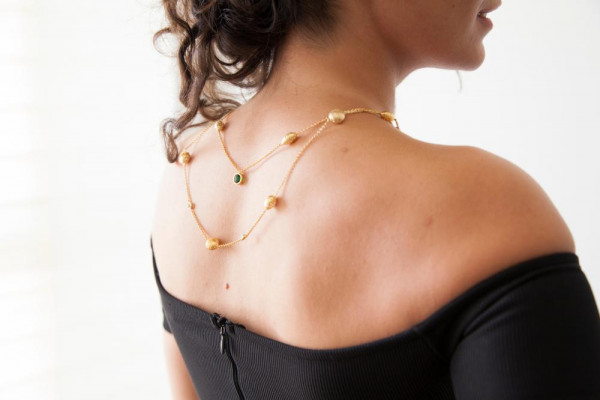 La mujer lleva un collar de oro para las damas en la espalda. Encuentra collares de oro en BAUNAT. 