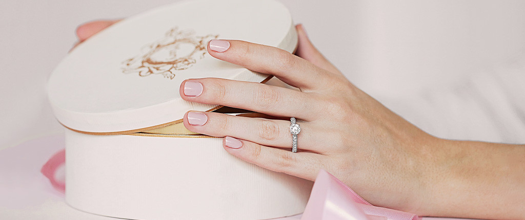 Une femme ouvre une boîte cadeau blanche avec un ruban rose - BAUNAT