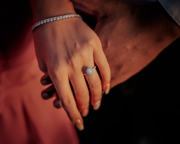 Nahaufnahme eines zarten Diamant-Armbands und eines tropfenförmigen Diamantrings aus Weißgold an einer Hand