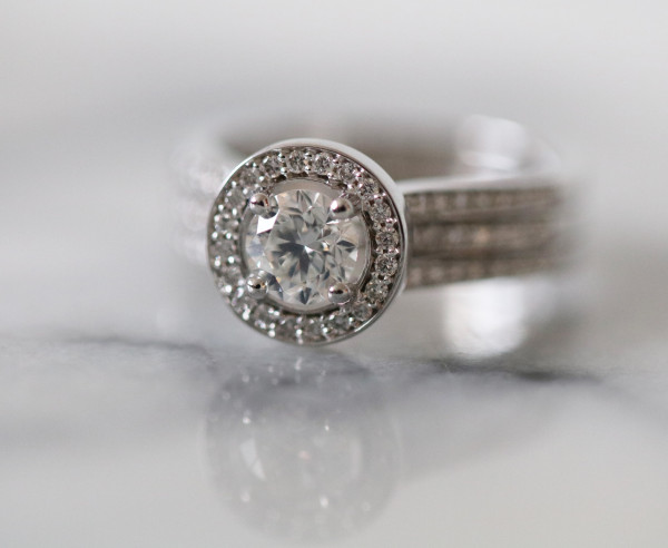 Anillo de compromiso de oro blanco con diamante central ovalado y halo de diamantes pavé