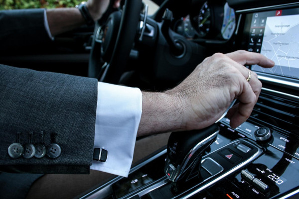  El hombre está sentado en el coche y lleva gemelos. Los gemelos son un buen regalo para el padrino de una comunión - BAUNAT