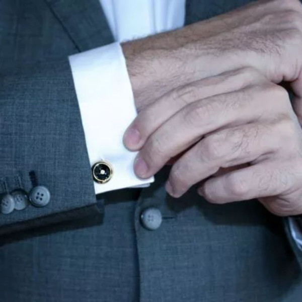 un reloj y una alianza BAUNAT - Hombre vestido con traje y gemelos, lleva puesto un reloj y una alianza de BAUNAT.