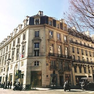Edificio parisino de piedra beige con mansarda y balcones, en esquina de calle elegante