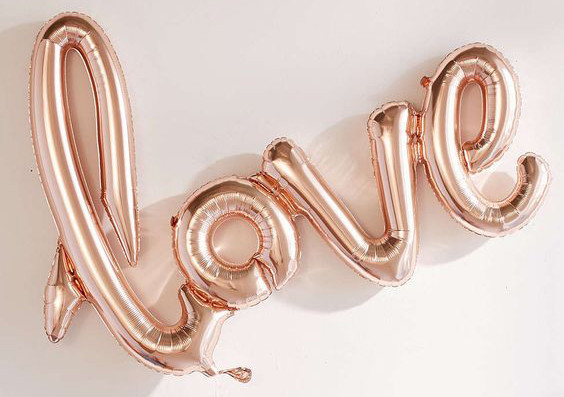 Globo metálico rosa dorado con la palabra “love” en letras cursivas