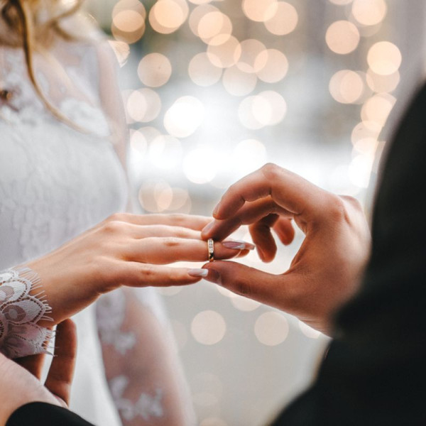 Bräutigam in christlicher Tradition, der den diamantenen Ehering der Braut in die rechte Hand schiebt - Der Bräutigam steckt seiner Braut den Ehering an den rechten Ringfinger.
