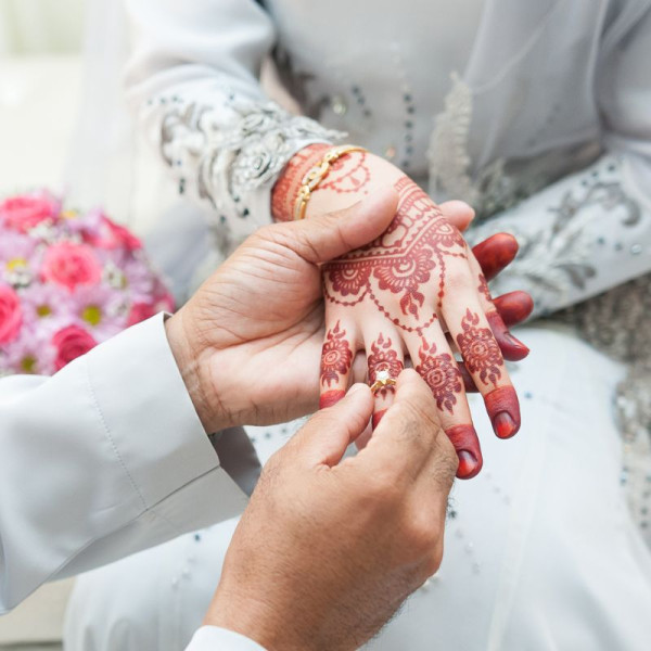 Bräutigam schiebt in islamischer Tradition den diamantenen Ehering der Braut an den Ringfinger ihrer geschmückten rechten Hand - Ein Ring wird auf den rechten Ringfinger aufgesteckt.