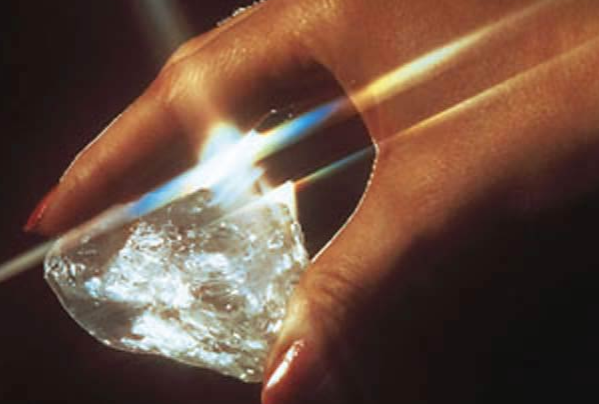 Een vrouw die de Star of Sierra Leone diamant vasthoudt, die een helder licht uitstraalt.