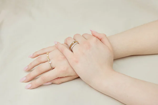 a woman wearing stackable rings in red and white gold on her hand, a perfect mix and match