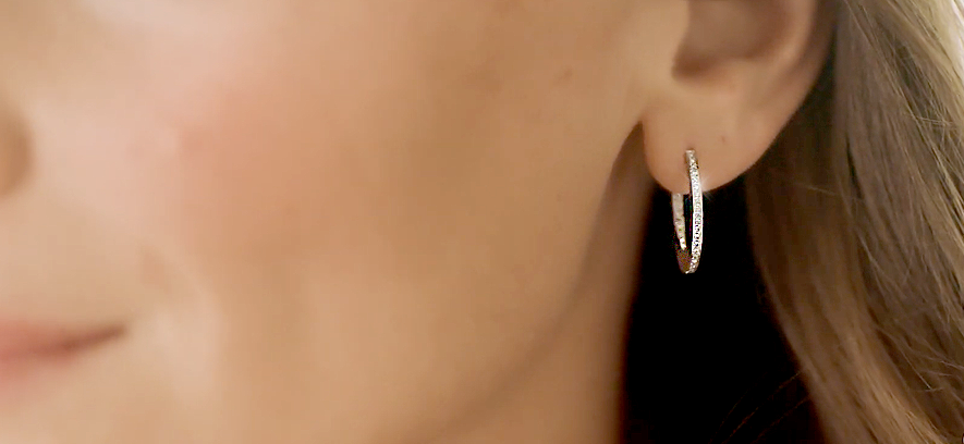 Close-up van een kleine gouden hoepeloorbel met fijne pavégezette diamanten