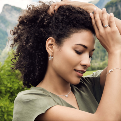 BAUNAT - Eine Frau mit lockigem Haar, trägt elegante Ohrringe aus der Monarca-Kollektion.