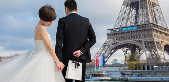BAUNAT - Mann, der vor dem Eiffelturm einen Heiratsantrag machen will und eine BAUNAT-Tasche mit einem diamantenen Verlobungsring in der Hand hält


