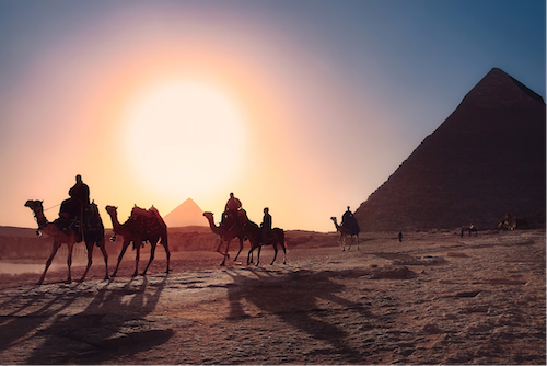 De zon zakt onder de piramides van Gizeh en schildert de lucht met levendige kleuren in dit iconische tafereel uit het oude Egypte.