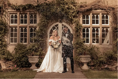 Les mariés, vêtus d'une tenue de mariage anglaise classique, posent devant un charmant lieu de mariage anglais
