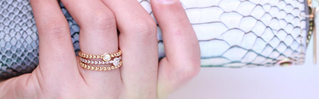 een vrouw draagt drie stapelbare ringen van elk een ander edelmetaal