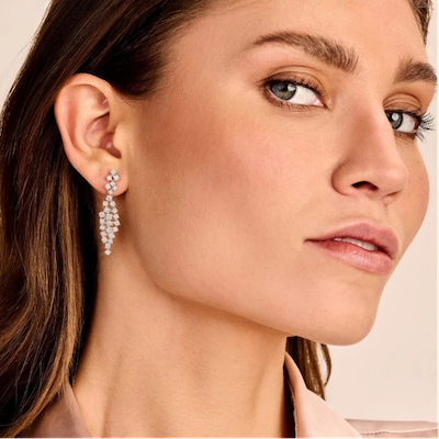femme portant d'élégantes longues boucles d'oreilles pendantes avec des diamants blancs étincelants qui captent magnifiquement la lumière