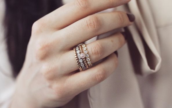 Gros plan d'une femme portant des bagues empilables BAUNAT de différentes couleurs dorées, des bijoux appropriés pour un cadeau de Noël.