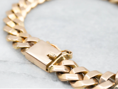 Een gouden schakelarmband met een veilige spansluiting, elegant ontworpen voor een verfijnde look.