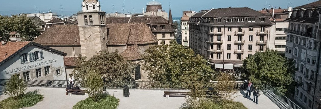 Paysage urbain pittoresque de Genève mettant en valeur une église et une tour d'horloge, avec le showroom Baunat ajoutant du charme à la scène.