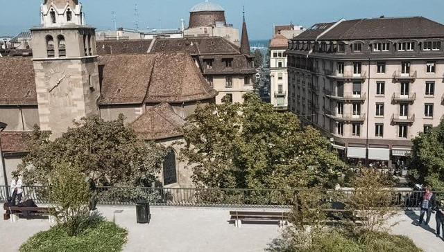 Paysage urbain pittoresque de Genève mettant en valeur une église et une tour d'horloge, avec le showroom Baunat ajoutant du charme à la scène.