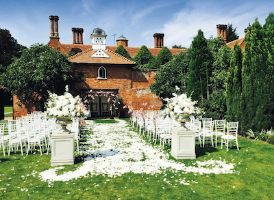 Eine charmante Hochzeit auf dem Land vor einem rustikalen Backsteingebäude, geschmückt mit Blumen und elegantem Dekor, der perfekte englische Hochzeitsort
