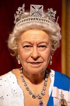 Ein Porträt der verstorbenen Königin Elizabeth II., die eine Perlen- und Diamantkrone, eine Halskette aus großen Diamanten und eine Anstecknadel ihres verstorbenen Ehemanns trägt.