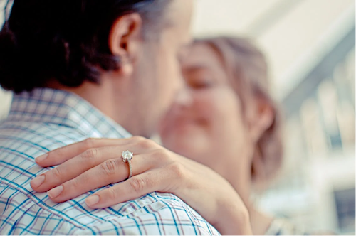 Paar, das sich umarmt, nachdem der Ehemann einen Heiratsantrag mit einem atemberaubenden Diamant-Verlobungsring gemacht hat