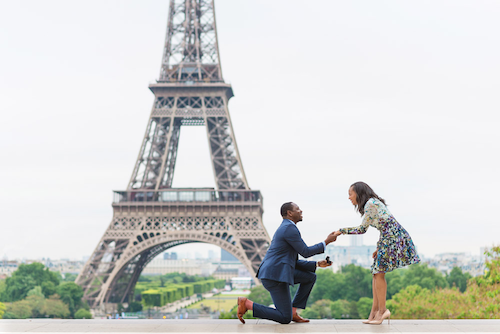 un homme pliant le genou devant la Tour Eiffel, célèbre lieu de demande en mariage à Paris