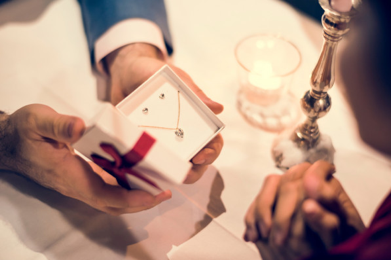 Un uomo regala un gioiello a una donna. Trova il gioiello perfetto per il tuo anniversario di matrimonio da BAUNAT.