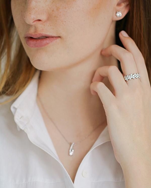 Donna elegante che indossa una sottile collana in argento con diamanti e una camicetta bianca, per un look di classe.